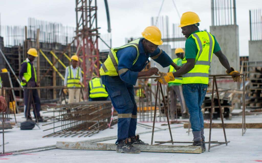 A diverse group of construction workers in safety gear at an active building site.